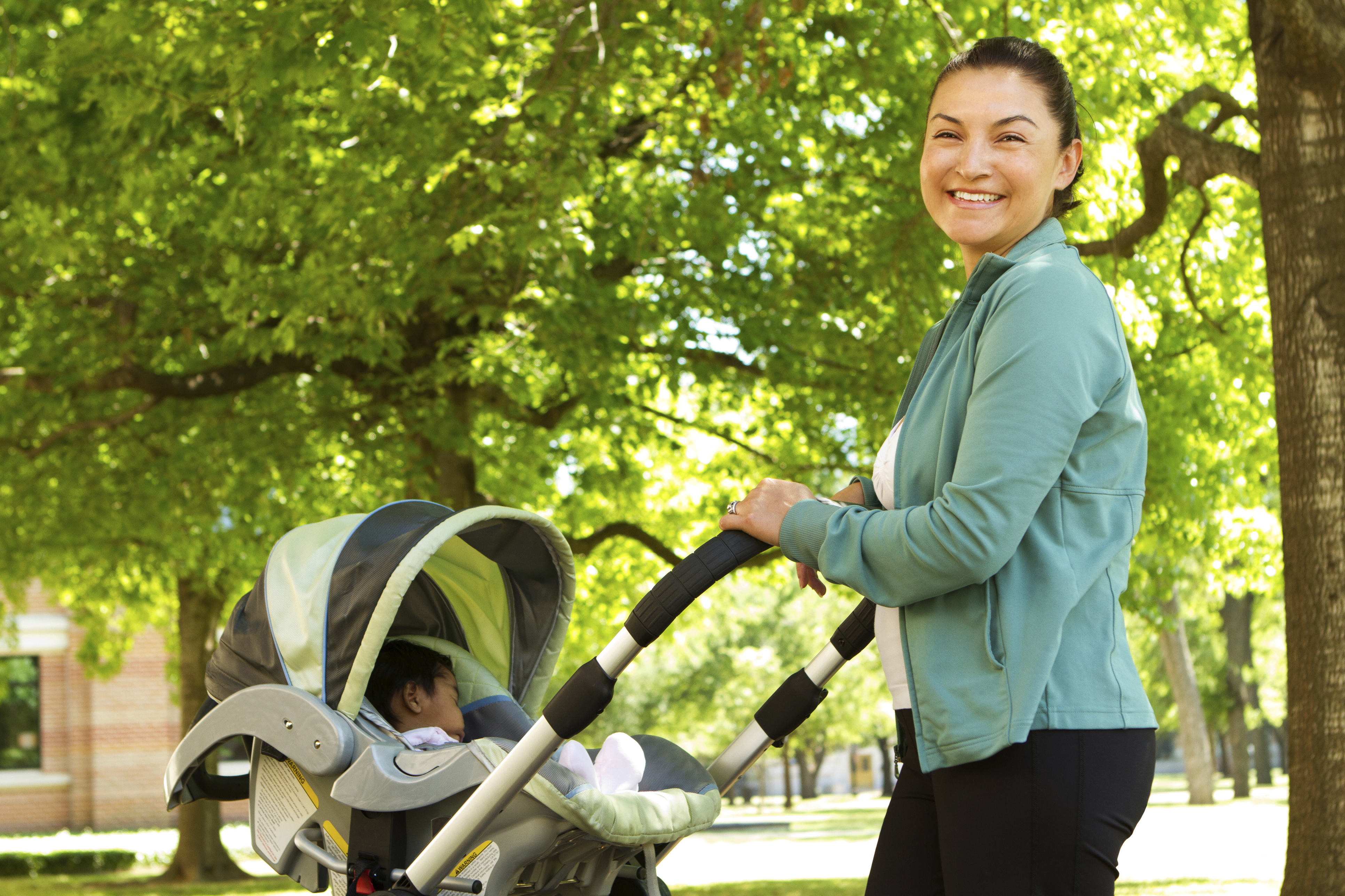 Smiling mother taking baby for walk on campus.